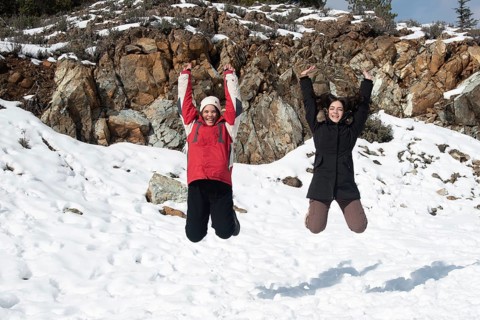 Two young happy teenage girls jumping with pleasure at snow. Troodos mountains Cyprus