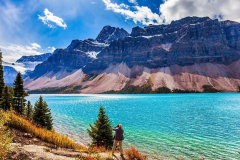 The Majestic Rockies of Canada. A gray-haired tourist photographs a grandiose landscape. Lake Bow