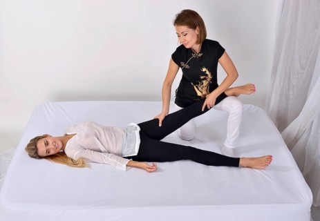 Thai massage. Massage therapist works with patient and massages her body. Studio shot