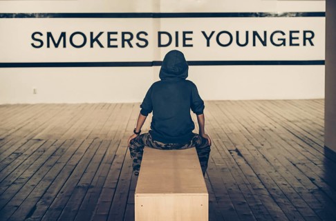 Teenager smoking and message on wall - Smokers die younger. No smoking concept with child. Casual