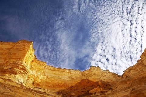 Edges of a canyon from dry sandstone on a background of the cloudy sky