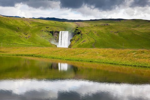 An incredible reflection. Abounding waterfall Skogafoss reflected in a small pond near the road