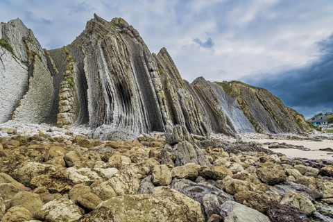 Portio Beach, Cantabria Beaches. Giant rough gray rocks and smooth sandy beach. Noon on the beach
