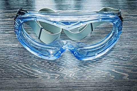 Safety plastic goggles on wooden board