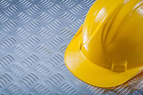 Safety hard hat on channeled metal background construction concept