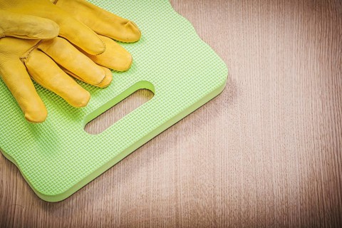 Safety leather gloves garden foam kneeling pad on wooden board gardening concept