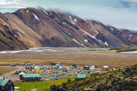 Pink and green rhyolite mountains surround the flat valley of the National Park Landmannalaugar.