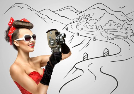 Glamorous pin up girl filming nature and landscape with an old retro cinema 8 mm camera, standing