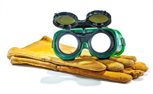 Welder working goggles on pair of gloves isolated