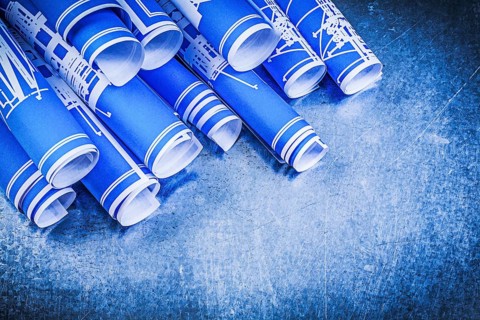 Pile of blue blueprints on metallic background construction concept