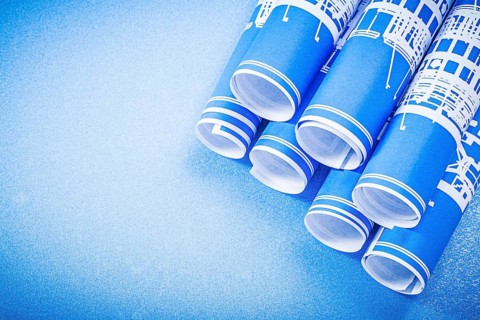 Stack of engineering drawings on blue background top view