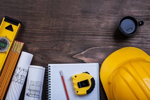 Workbook pencil cup of coffee and construction objects on wooden board maintenance concept
