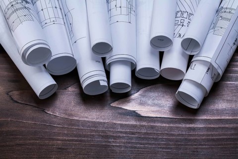 Pile of blueprint rolls on pine wooden vintage board maintenance concept