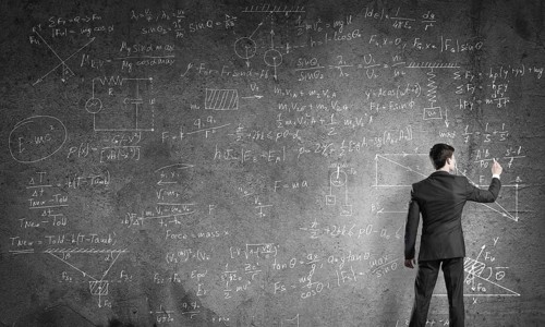 Man in suit standing with back and drawing physics formulas