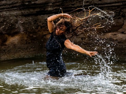 Middle-aged woman dancing and throwing water in the air, Maioris beach, llucmajor, Majorca,