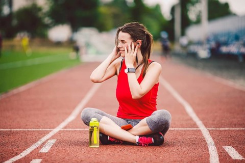 Theme healthy lifestyle, sports music. beautiful young Caucasian woman rests sitting treadmill