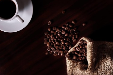 Coffee still life with cup, coffee beans in bag. Low key light