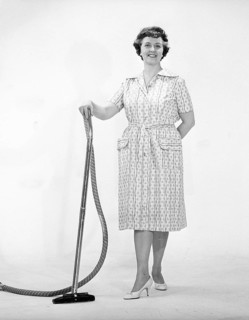 Cleaning day in the 1960s. A woman is standing holding a vacuum cleaner, looking happy. Sweden