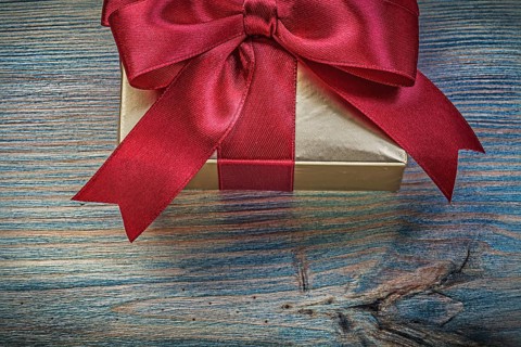 Present box in glittery paper on vintage wooden board holidays concept