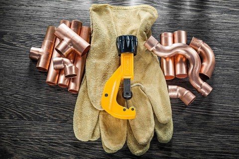 Plumbing water pipe scissors leather safety gloves on wooden board top view