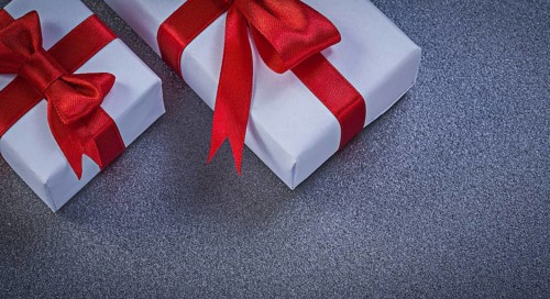 White giftboxes with red knots on grey surface holidays concept