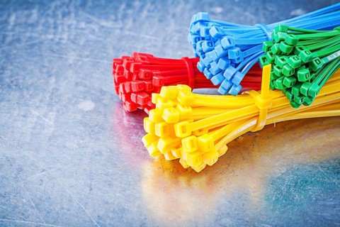Multicolored plastic tying cables on metallic background construction concept