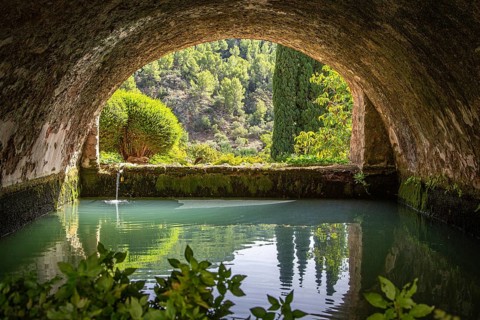 Tranquil, arched tunnel with views of water and trees in the background, Jardines de Alfabia