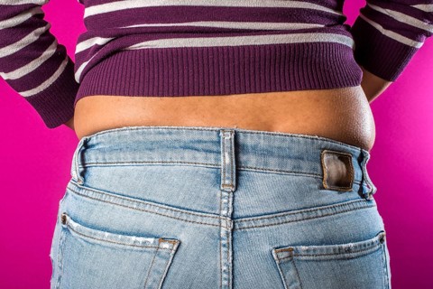 Woman with jeans shows her belly. Overweight