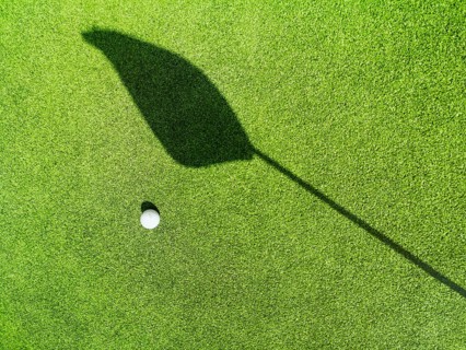 Golf ball on the green, shadow of a flag on a green, golf course