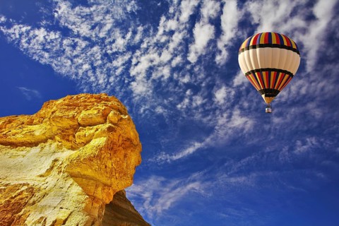 The bright decorative balloon flies above stone desert