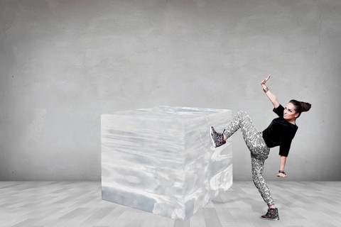 Business woman pushing big ice cube in the gray room