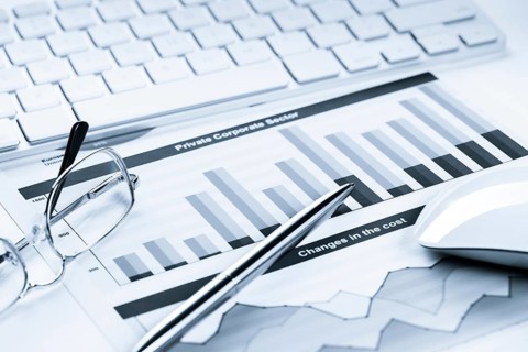 Business workplace with keyboard glasses and financial documents on table