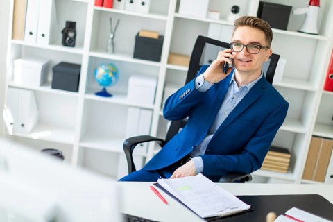 Casual businessman working in office, sitting at desk, typing on keyboard, looking at computer