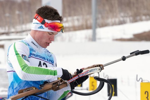 Biathlete reloads rifle before rifle shooting on shooting range. Sportsman biathlete Zlobin