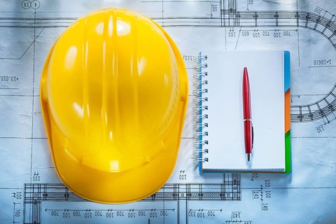 Protective building helmet notebook pen on blueprint
