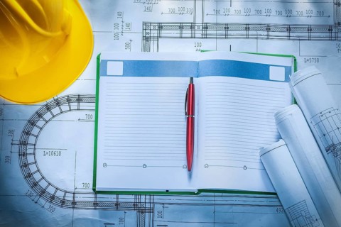 Pen hard hat construction drawings notepad on blueprint