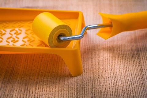 Roller on paint tray and wooden board