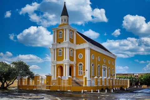 A view of a yellow church in willemstad on curacao with blue sky and nice clouds