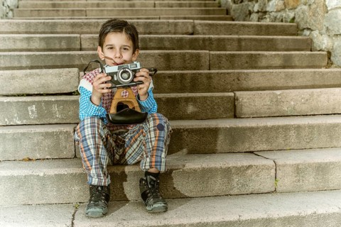 Child with vintage camera. Exterior stairs