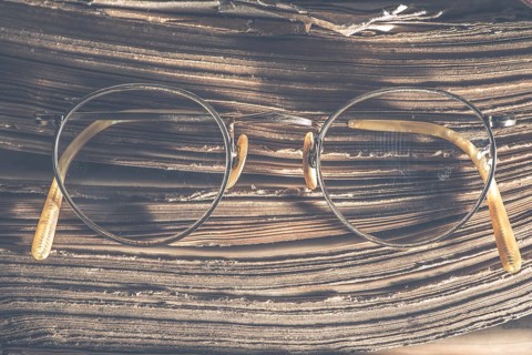 Old vintage round glasses and old book. Low light