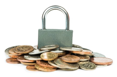 Grey locked padlock and coins. Isolated studio shot