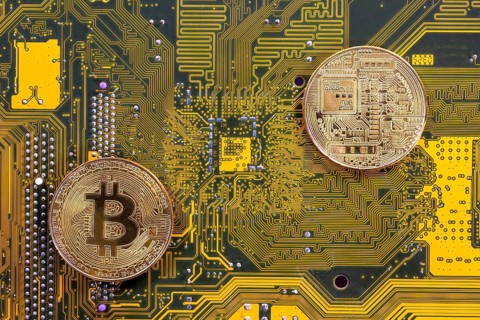 Virtual cryptocurrency money Bitcoin golden coins on a computer printed circuit board PCB. The