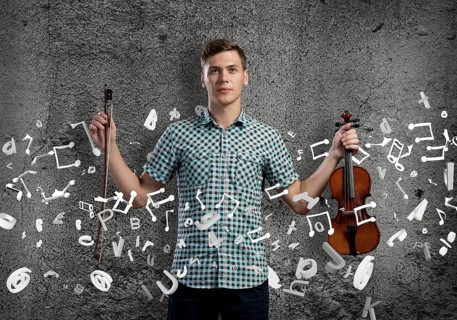 Young handsome guy on cement background with violin