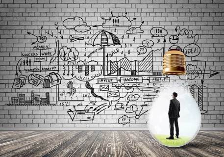 Businessman inside of light bulb in empty concrete room and sketches on wall