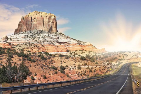 Gorgeous American Highway. Monument Valley in Utah on a cloudy windy day. Shining rays of evening