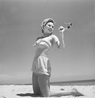 1940s summer. A young woman by the sea is getting a nice suntan. She is wearing a typical 1940s