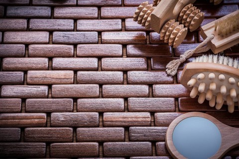 Looking-glass massagers and peeling brushes on textured wooden table mat sauna concept