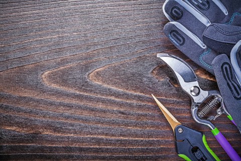 Working gloves metal garden shears pruner on wooden board