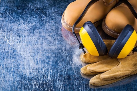 Leather waterproof boots protective gloves and noise reduction ear muffs on scratched metallic