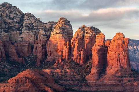Towering red rock formations in a desert landscape with warm sunset lighting casting long shadows